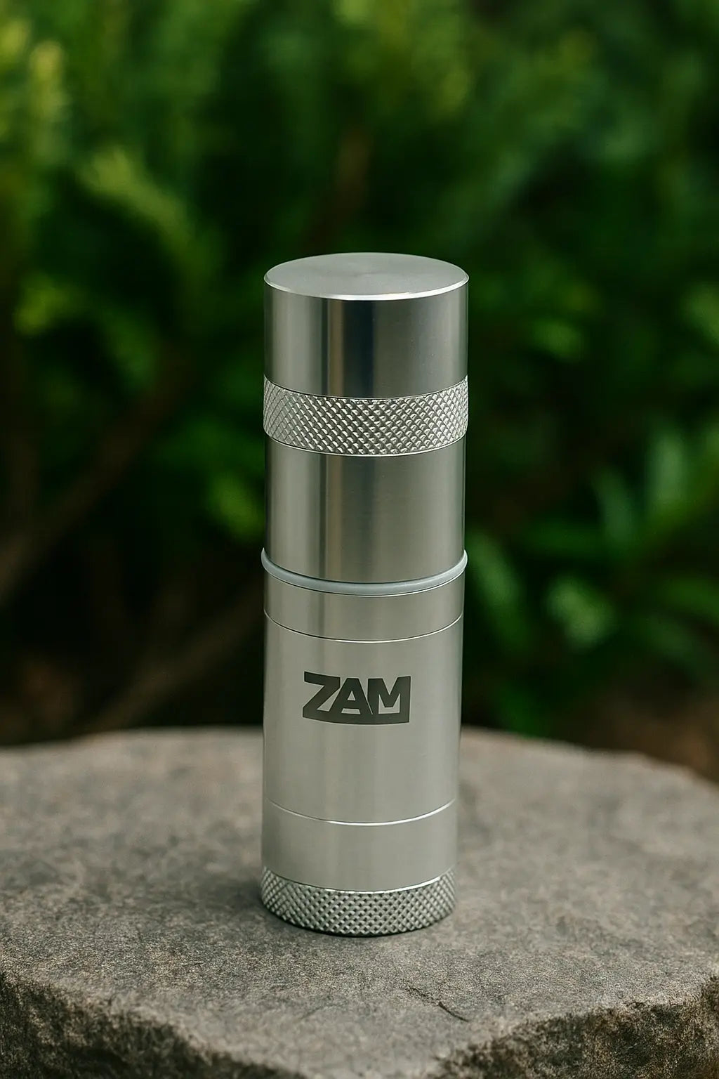 zam pocket grinder standing on a stone with green vegetation in background